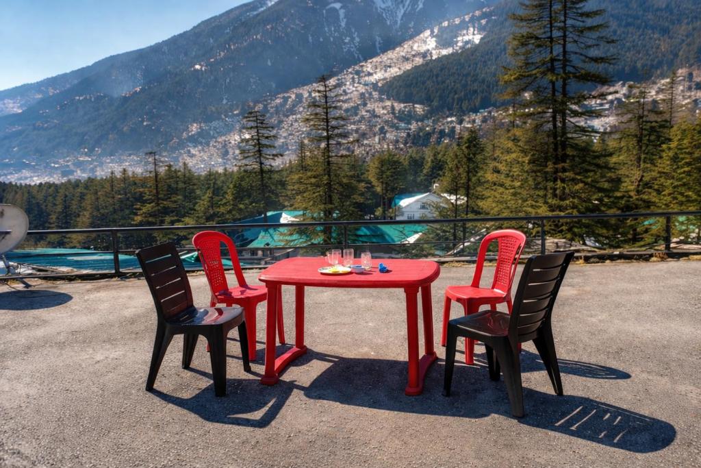 a red table and four chairs on a patio with a view at Apple Garden Aleo in Manāli