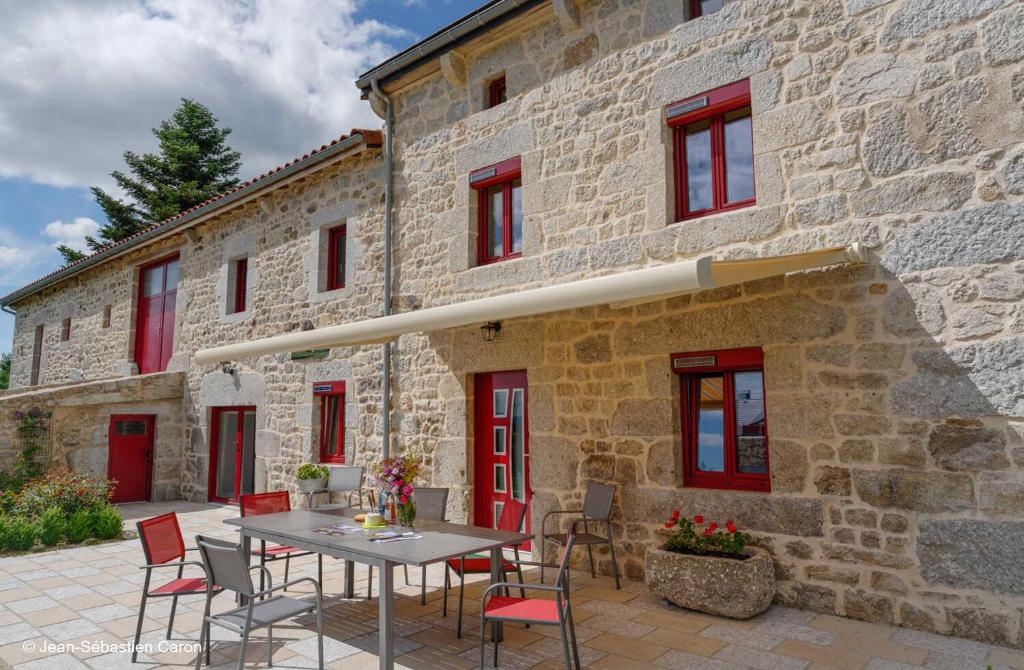a patio with a table and chairs in front of a stone building at Gîte la margeride 4 personnes in Julianges