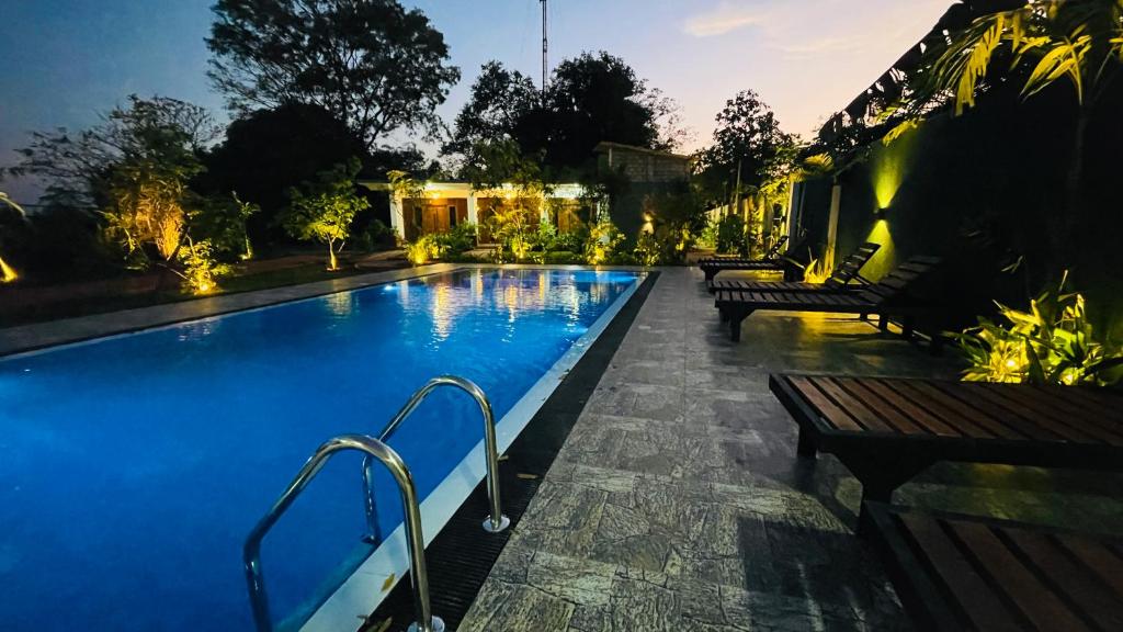 a swimming pool at night with benches around it at Aloria Sigiriya in Sigiriya