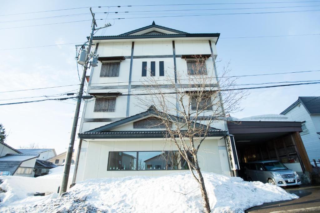 a tall white building with snow in front of it at Matsuya hotel in Myoko