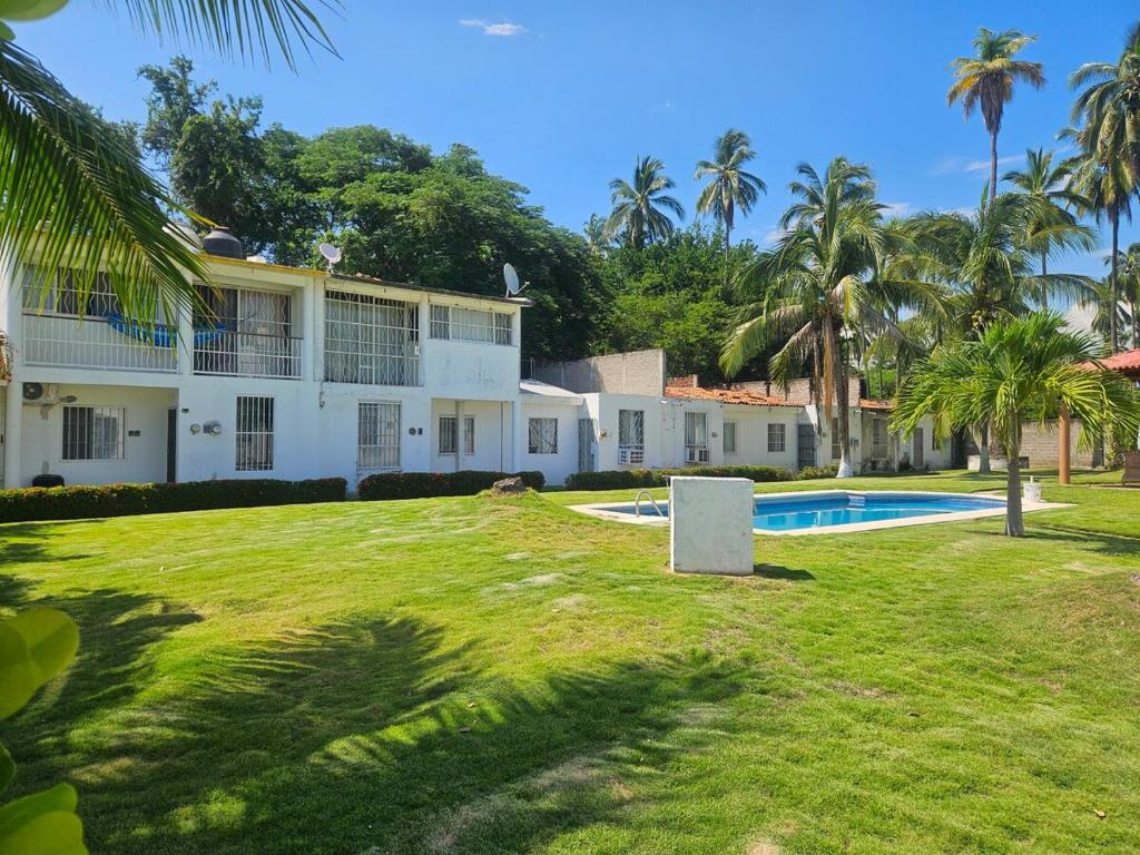 a large white house with a pool and palm trees at Casa Golden in Barrio Nuevo