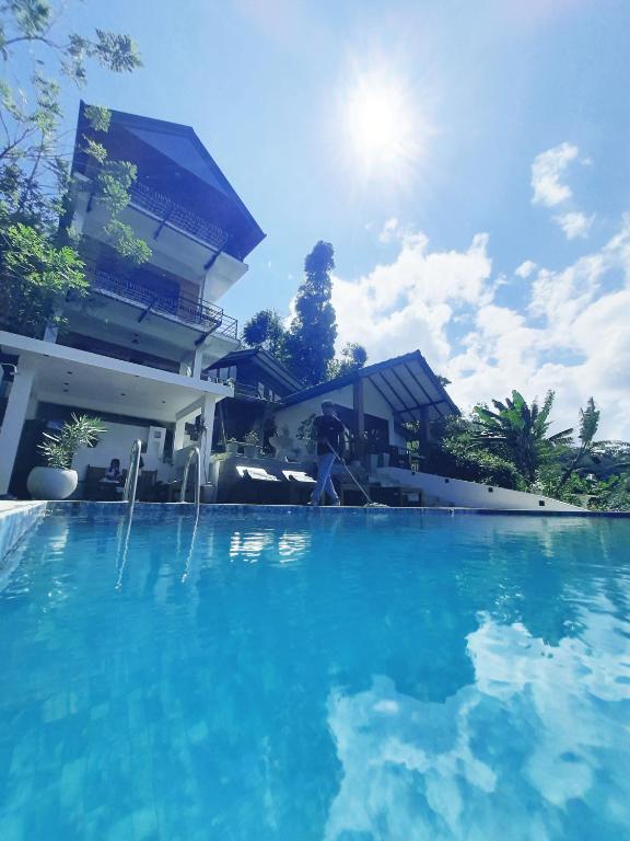 a person standing near a swimming pool in front of a building at Idyll Cottage Ella in Ella