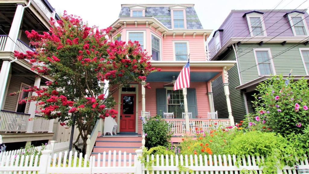 a pink house with a white fence and flowers at Cottage At 37 Jackson in Cape May