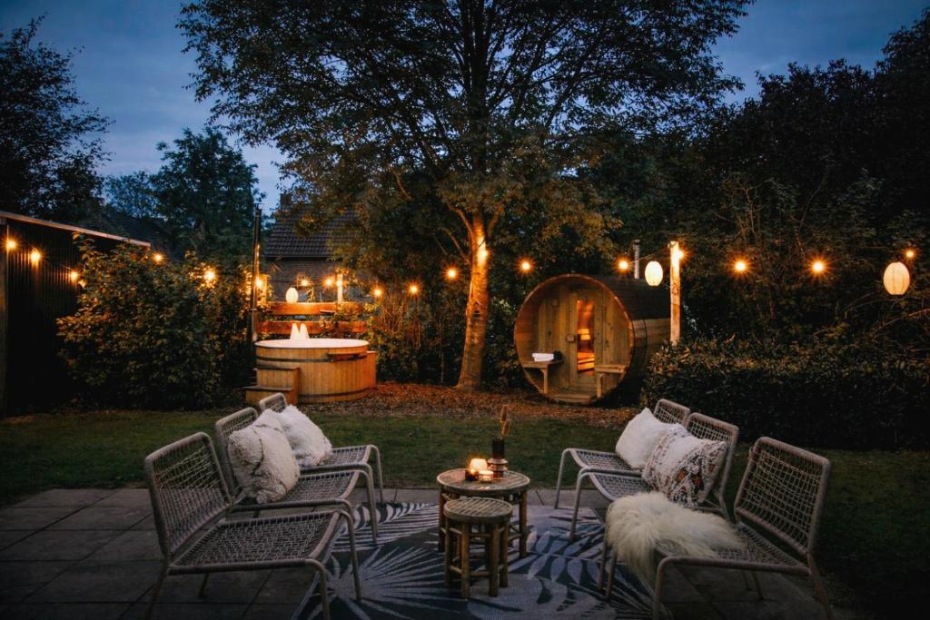 a patio with chairs and a table with lights at Bohemian Wellness met hottub & sauna in Ewijk
