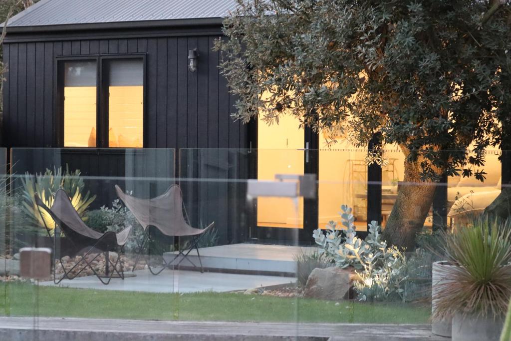 a house with glass windows and two chairs in front of it at Driftwood Studio in Mount Martha