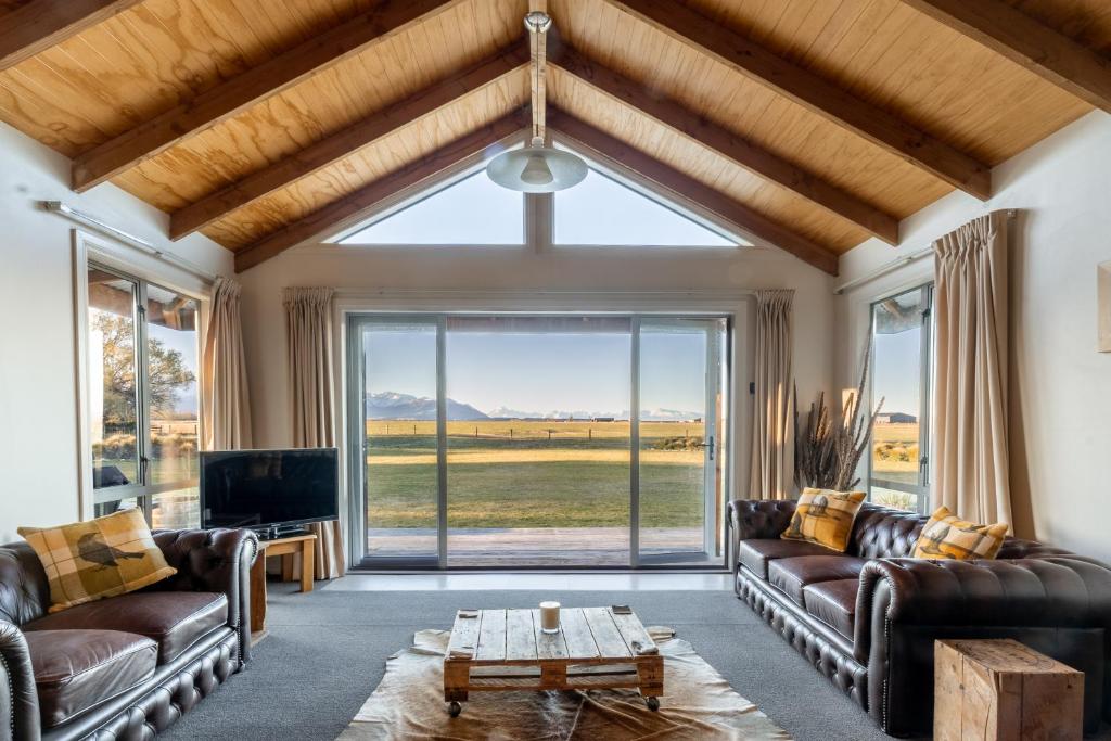a living room with leather couches and a large window at Omahau Down in Lake Pukaki