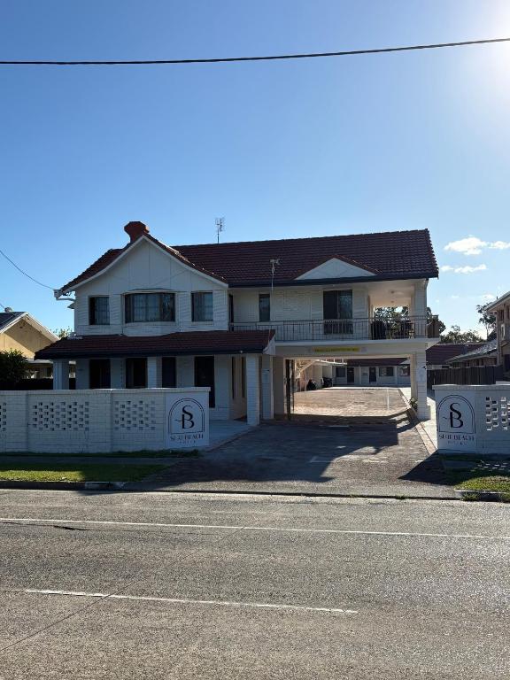 a large white house with a fence in front of it at Surf Beach Motel Tweed in Tweed Heads