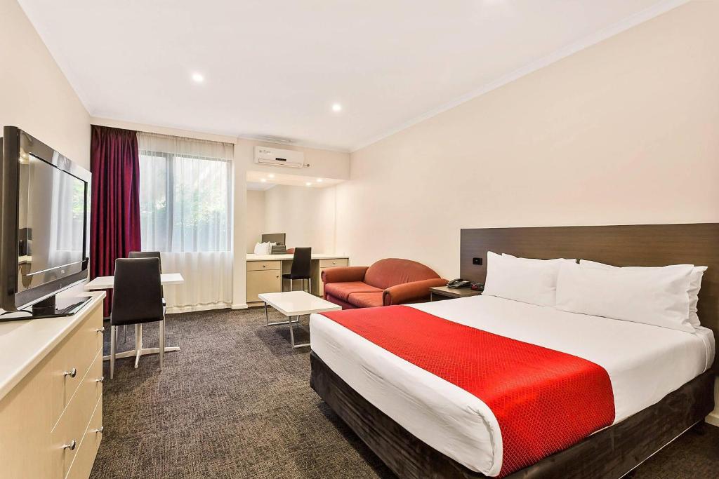a hotel room with a large bed and a desk at Quality Hotel Manor in Mitcham