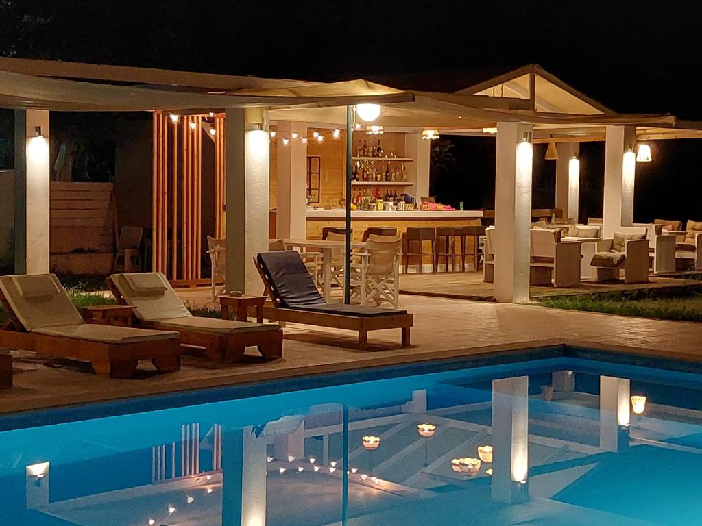a swimming pool with lounge chairs and a house at Amelia's Garden ΙΙ in Kavos