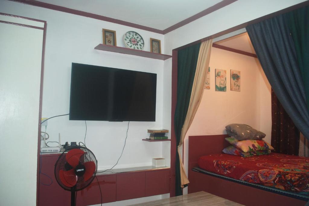 a bedroom with a flat screen tv and a fan at Charm Condo Just Steps from Enchanted Kingdom Sargas in Santa Rosa