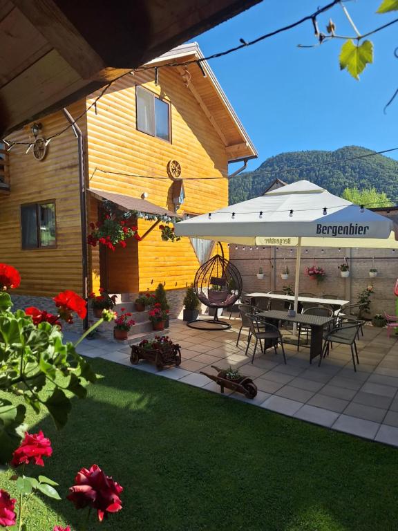 a house with a patio with a table and an umbrella at Cabana Rustica Georgeta in Zărneşti