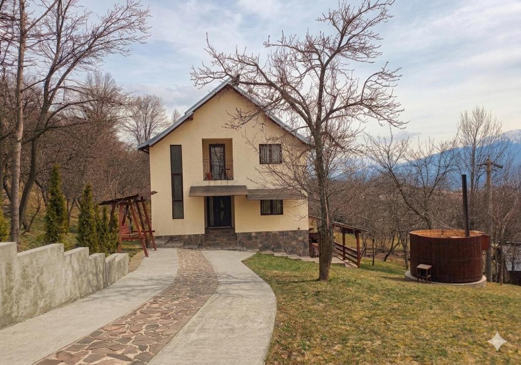a white house with a tree and a sidewalk at Casa Fluțar in Moisei