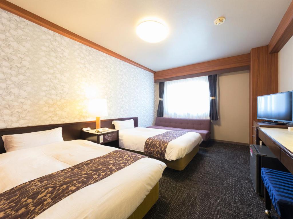 a hotel room with two beds and a flat screen tv at Hotel Anesis Seto-Ohashi in Utazu