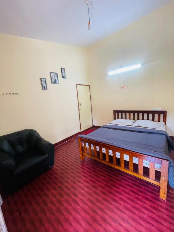 a bedroom with a bed and a black chair at Villa Mountain Pearl in Chikmagalūr