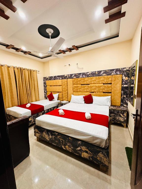 a bedroom with two beds with red and white sheets at New Like Home Hotel in Lahore