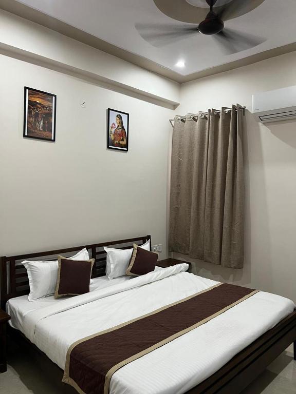 a bedroom with a large bed with a ceiling fan at Bhavya Guest House in Rīngas