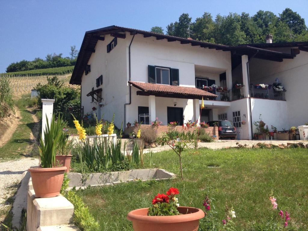 ein weißes Haus mit Blumen im Hof in der Unterkunft Alba Raimondo House in Santa Vittoria dʼAlba