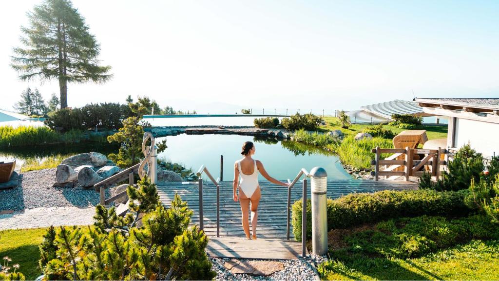 a woman in a bikini walking down the stairs to a pool at Mountain Resort Feuerberg in Bodensdorf
