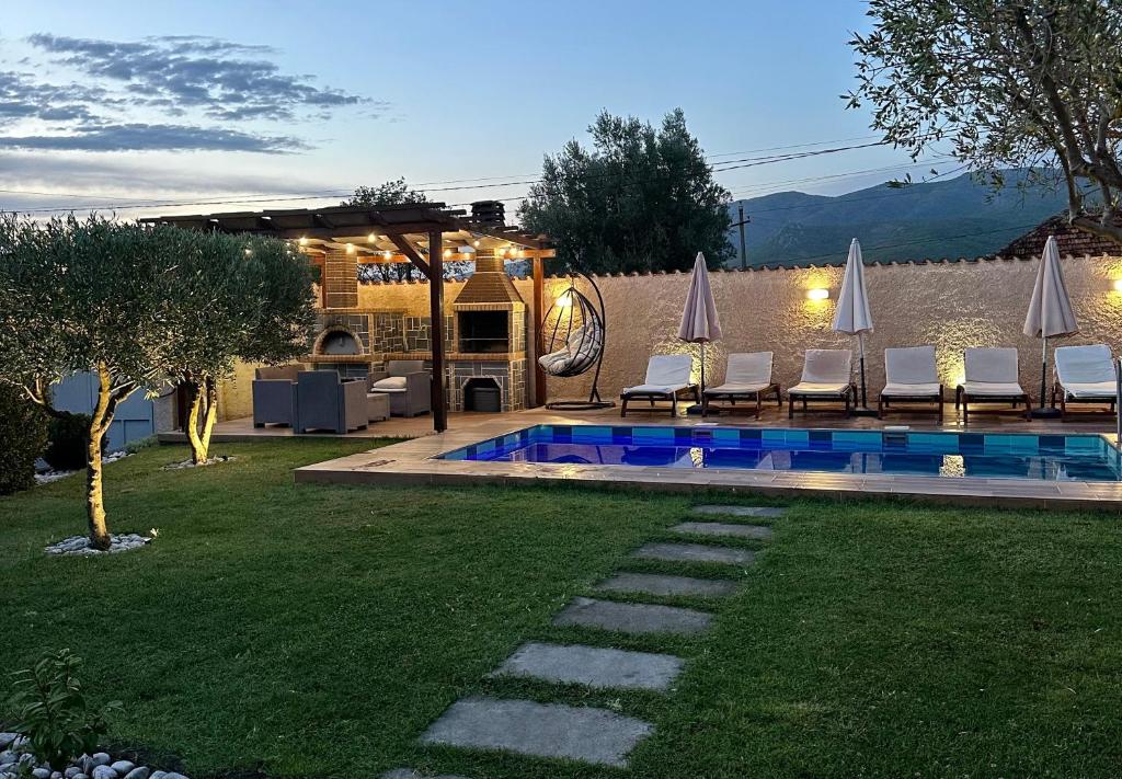 a backyard with a swimming pool with chairs and umbrellas at Kallmet Villa in Kalmet