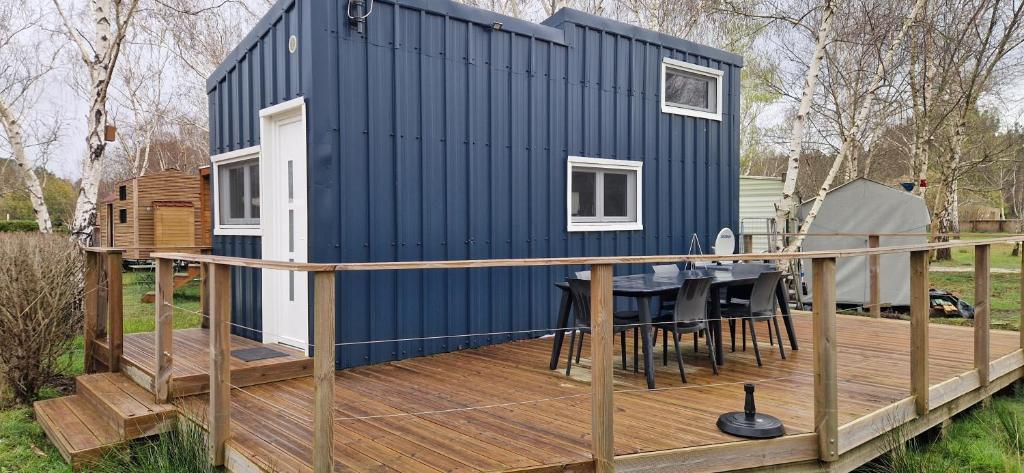 ein kleines Haus auf einer Terrasse mit einem Tisch in der Unterkunft Tiny bleu in Naujac-sur-Mer