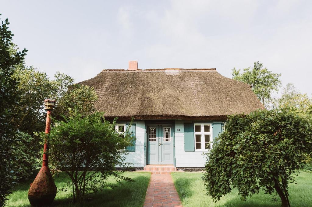 a blue house with a thatched roof and a brick path at Kapitänshaus Wieck in Wieck