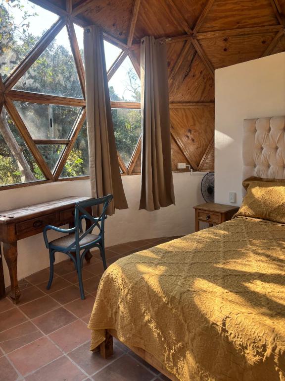 a bedroom with a bed and a desk and windows at Glamping in Malinalco in Malinalco