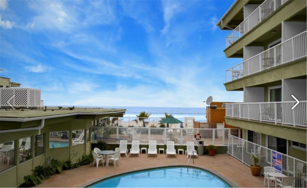 
a beach with a pool, chairs, and a balcony at Surfer Beach Hotel in San Diego

