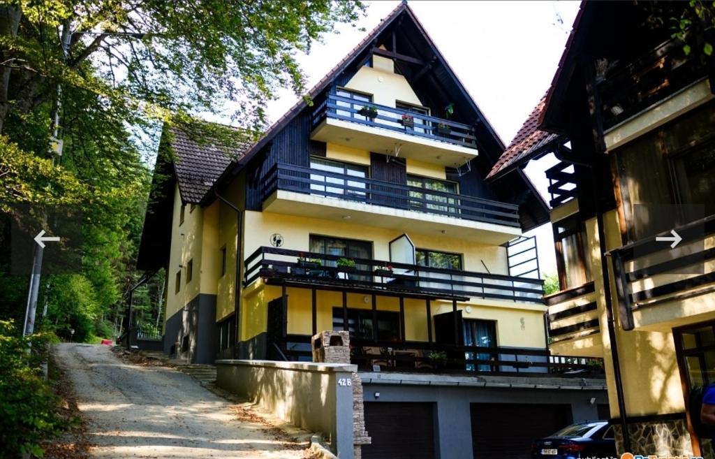 a large yellow and white building with a driveway at Apartament Kalinderu K1 Bușteni in Buşteni