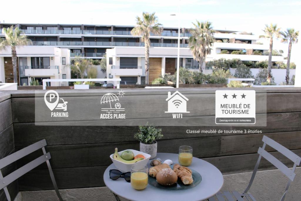 a table with a bowl of fruit and a plate of food at Playa Serena - Meublé de tourisme 3 étoiles - Accès Plage & Parking Privé in Carnon-Plage