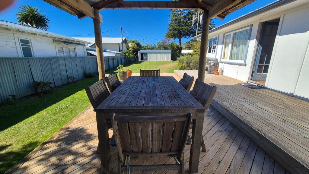 a wooden table and chairs on a deck at Bach 30 at Waimārama Beach in Waimarama