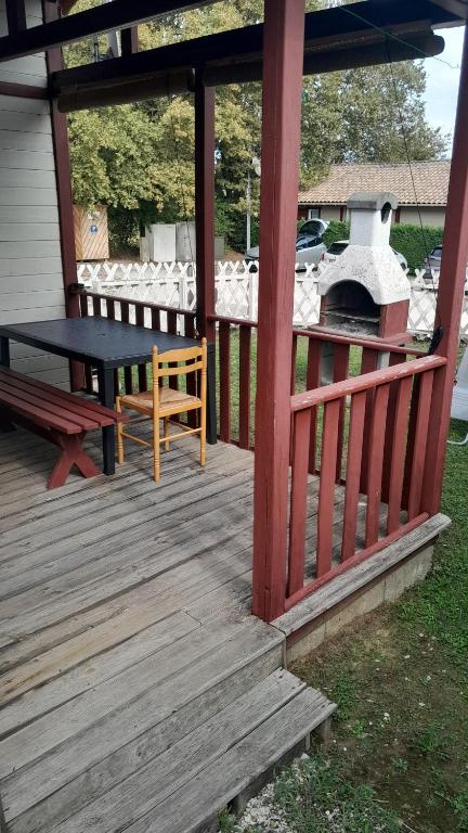 a wooden porch with a picnic table and a bench at Le chalet Paradis in Estang