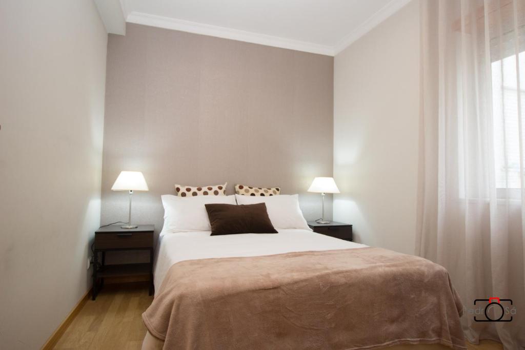 a bedroom with a large white bed with two lamps at Marnoto´s City Apartment in Aveiro