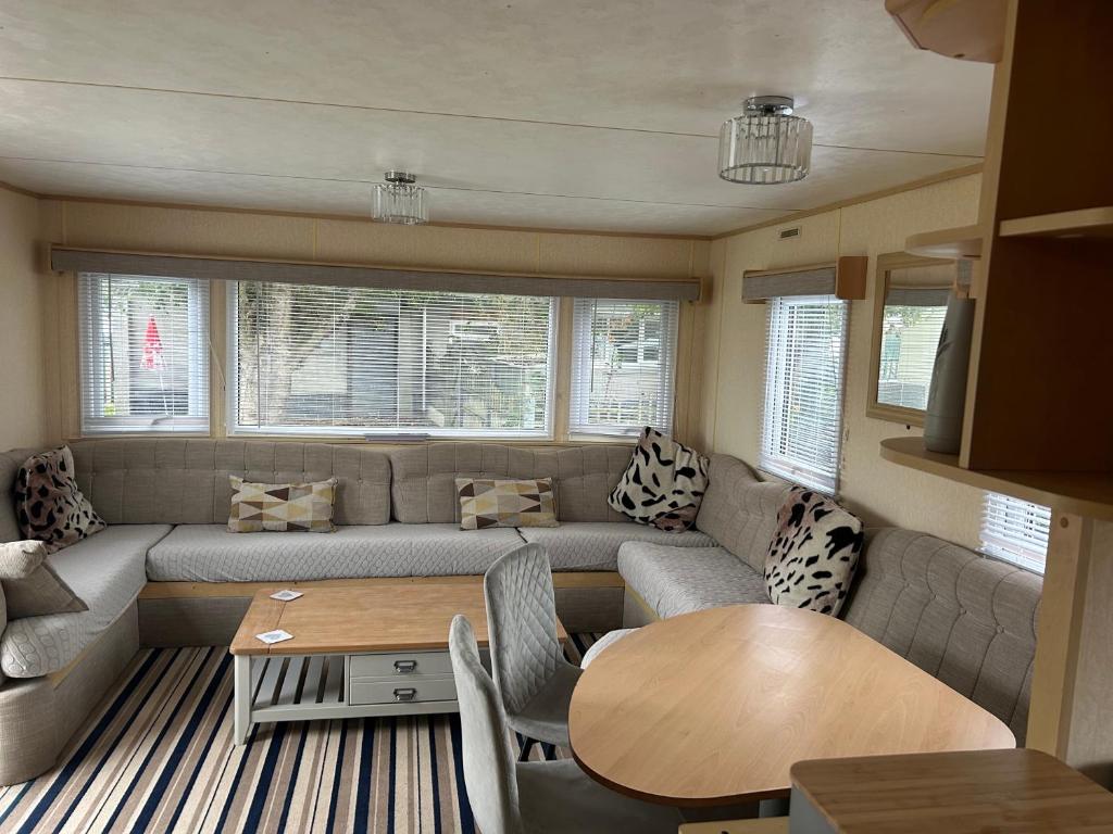 a living room with a couch and a table at Happy Days Caravan Park - Lovely Spacious 3 Bed Caravan in Chapel Saint Leonards