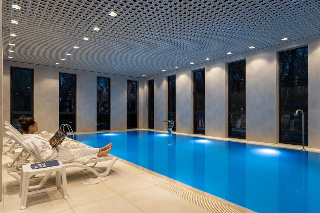a woman sitting in a chair next to a swimming pool at Marhaba Hotel & Spa in Tashkent