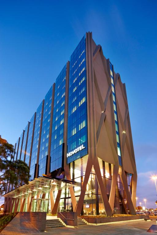 a large glass building with a sculpture in front of it at Novotel Auckland Airport in Auckland