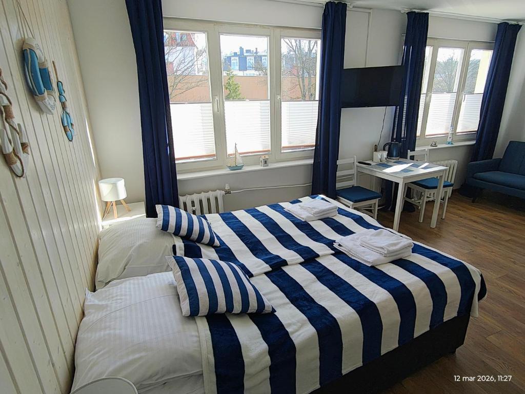 a bedroom with a bed with a blue and white striped blanket at Gryfhaus - Pokój Bosmański, kameralny, 22 m2, parking, Wi-Fi, blisko morza, wysoka ocena 9,9 in Międzyzdroje