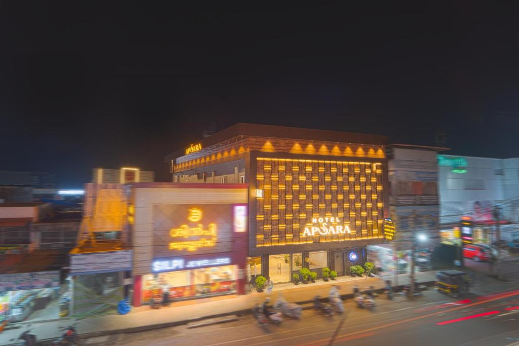 a lit up building on a city street at night at Hotel Apsara in Kizhake Chālakudi