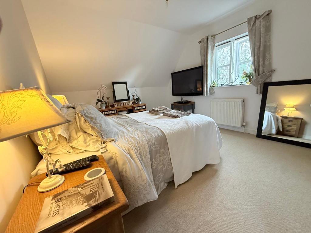 a bedroom with a bed and a table with a lamp at Silsoe Cottage B&B - Woodland View Room in Silsoe