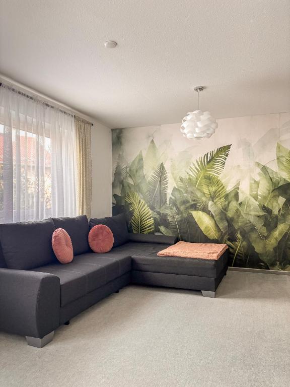 a living room with a couch and a mural of plants at Deluxe Apartment Ella in Backnang