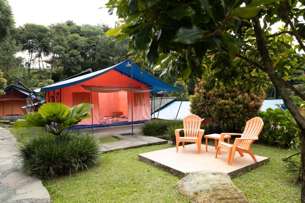 two chairs and a table in front of a tent at Glamping Camphills in Gunungpicung