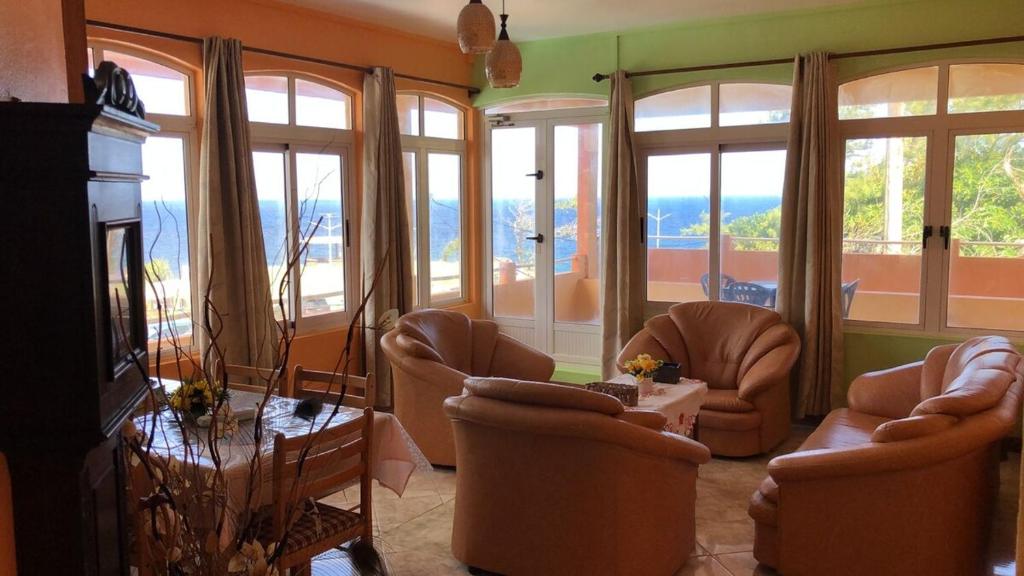 a living room with chairs and a table and windows at Escale Gris Gris, breathtaking views and location! in Souillac