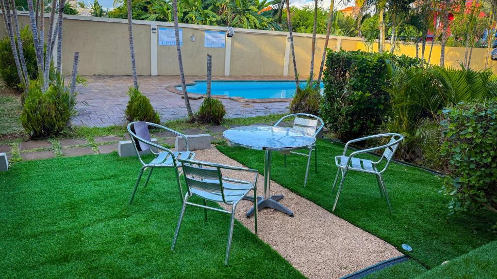 two chairs and a glass table in a yard at The Aviators Villa in Flic-en-Flac