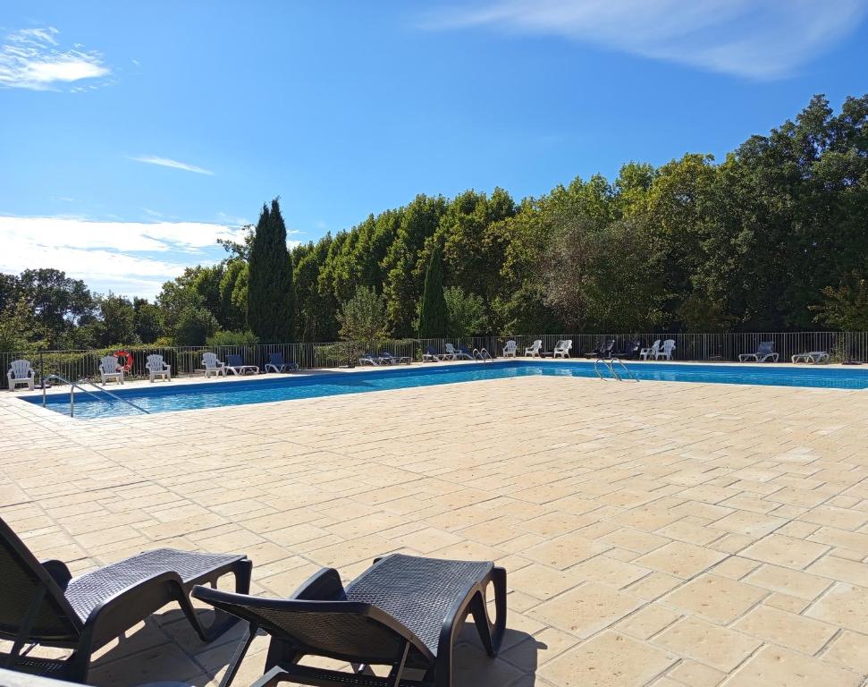 a patio with two chairs and a swimming pool at Le Chant des Cigales in Azille