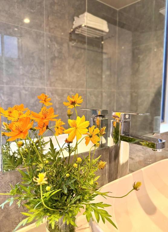 a vase filled with yellow flowers in a bathroom at PALM Minh Chau Hotel-Only for Vietnamese in Quang Ninh