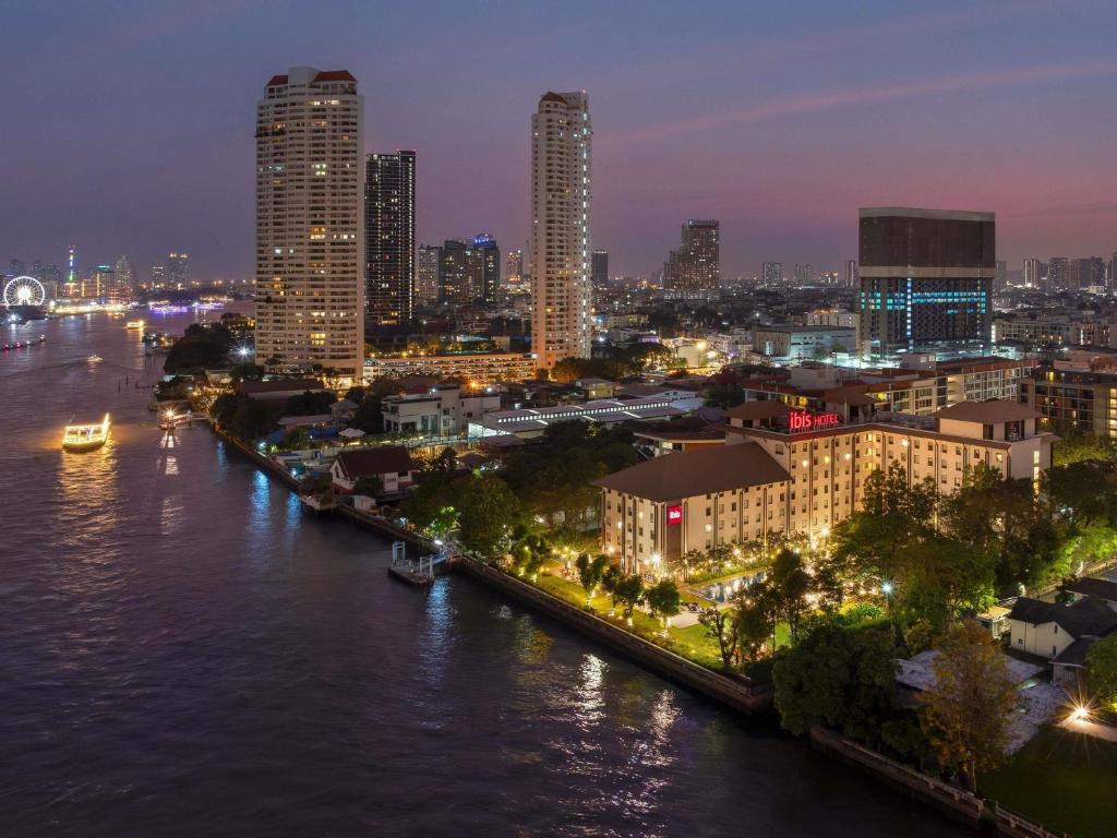 a city skyline at night with a river and buildings at Ibis Bangkok Riverside in Bangkok