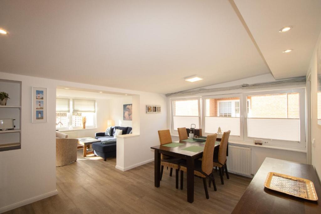 a dining room and living room with a table and chairs at Haus Roseneck App.1 in Hörnum
