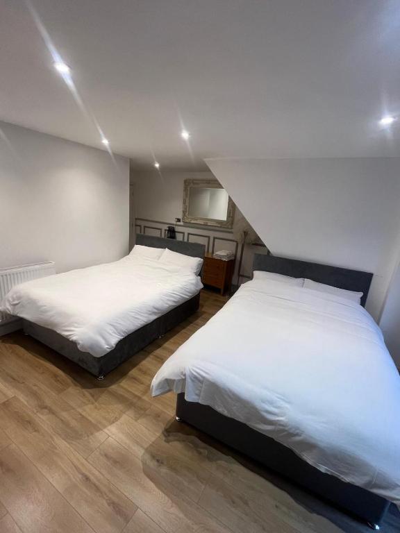 two beds in a room with white sheets at The Dublin Packet Room No6 in Holyhead