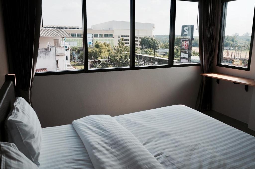 a bed in a bedroom with a view of a city at A3 Living in Suratthani