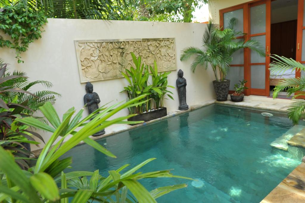 a swimming pool in front of a house with plants at Villa Ngetis in Sanur