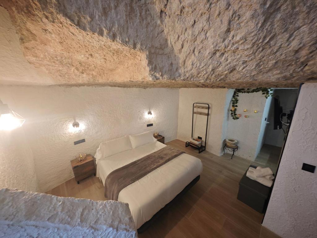 a bedroom with a large bed in a stone wall at Amonite in Alcalá del Júcar